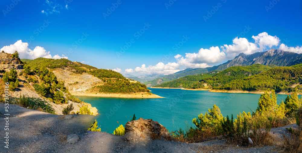Beautiful panorama of nature of mountainous region - a lake in a valley surrounded by mountain peaks and hills covered with forests.