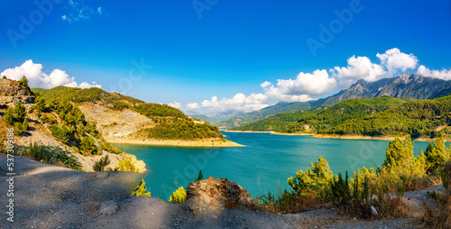 Beautiful panorama of nature of mountainous region - a lake in a valley surrounded by mountain peaks and hills covered with forests.