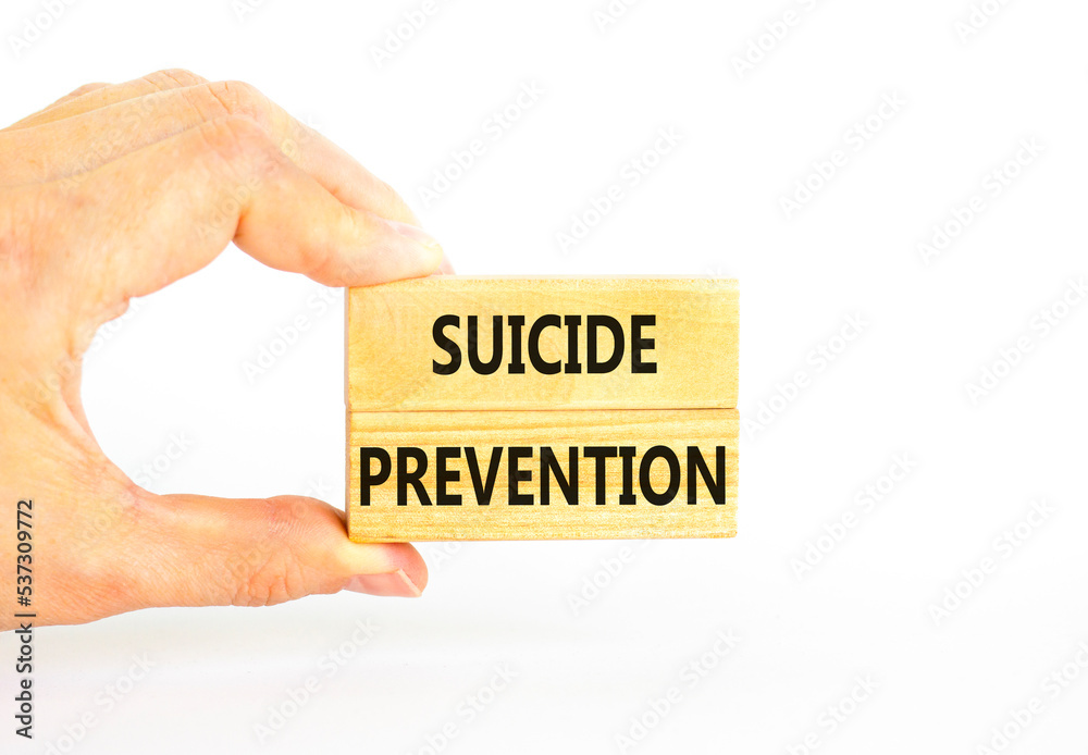 Suicide prevention symbol. Concept words Suicide prevention on wooden blocks. Beautiful white table white background. Psychologist hand. Psychological and suicide prevention concept. Copy space. Suicide prevention symbol. Concept words Suicide prevention on wooden blocks. Beautiful white table white background. Psychologist hand. Psychological and suicide prevention concept. Copy space.