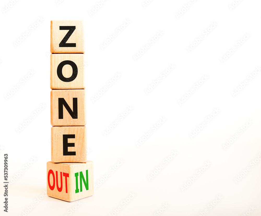 Zone in or out symbol. Concept words Zone in and Zone out on wooden cubes. Beautiful white table white background. Business zone in or out concept. Copy space. Zone in or out symbol. Concept words Zone in and Zone out on wooden cubes. Beautiful white table white background. Business zone in or out concept. Copy space.