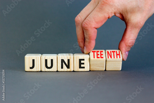 Juneteenth in June symbol. Concept words Juneteenth and June on wooden cubes. Beautiful grey table grey background. Businessman hand. Business Juneteenth in June concept. Copy space.