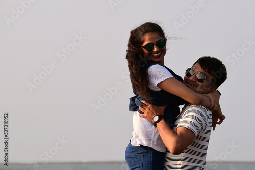 Closeup of a man lifting woman. Happy couple hugging each other at the sea beach. Romantic time and vacation for boyfriend and girlfriend.