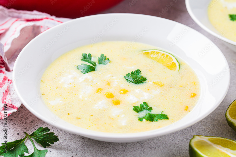 Plate of corn soup with cheese and herbs.