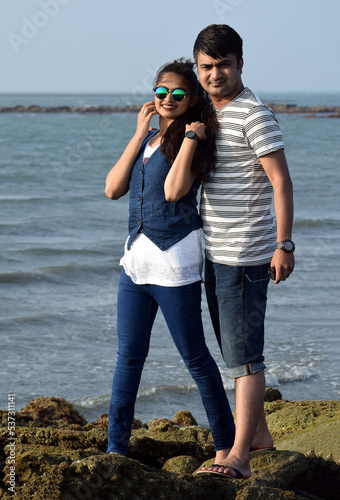 Asian young couple standing at the coral of a blue ocean. Romance at sea beach for newly married couple.
