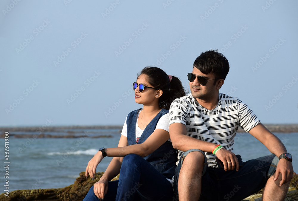 Closeup of a young couple enjoying a vacation of honeymoon. Man, and women sitting side by side at the sea beach