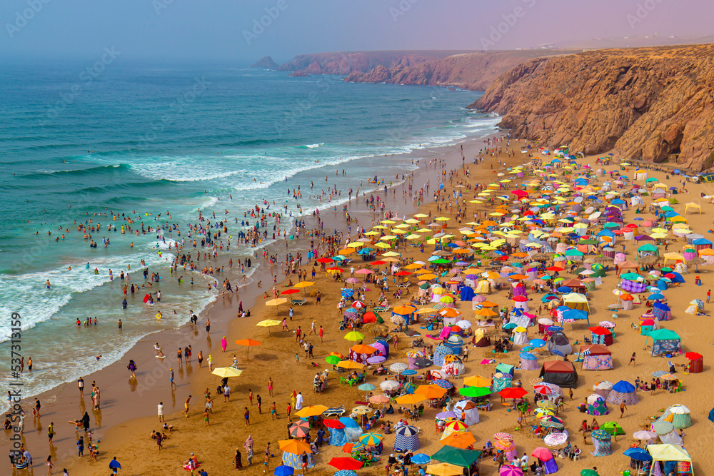 Aerial view of the beach with umbrellas and tourists at sunset, Mirleft, Morocco
