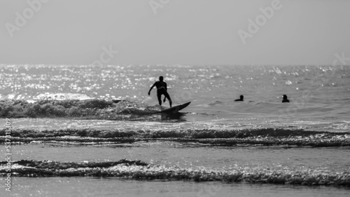 A man is surfing on a surfboard in Agadir beach in black and white