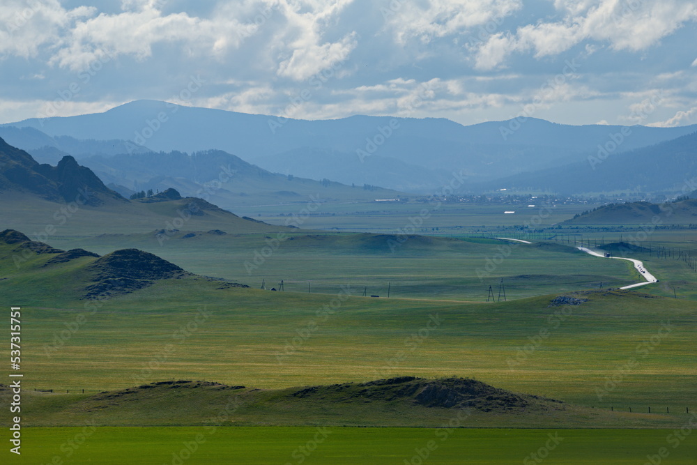 Fototapeta premium Russia. South of Western Siberia, Mountain Altai. Picturesque hilly mountains covered with a solid green carpet with many alpine flowers near the village of Ust-Kan.
