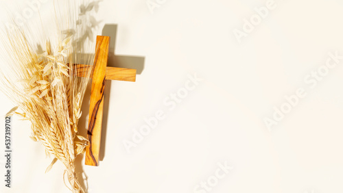 Canvas Print Wooden crucifixion with bouquet of wheat and rye on light background with copy space