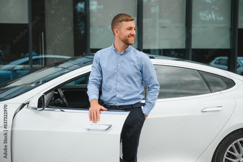 Businessman holding steering wheel while driving modern electric car on the street road. Confident man driving expensive car. Driver Turning Steering Wheel In Luxurious Auto On Trip Businessman holding steering wheel while driving modern electric car on the street road. Confident man driving expensive car. Driver Turning Steering Wheel In Luxurious Auto On Trip