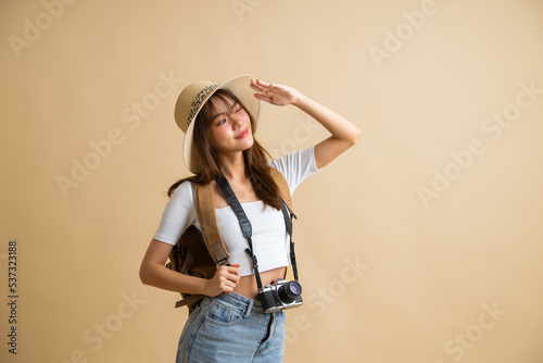 young attractive Asian woman traveler in casual clothes wearing straw hat with backpack and camera isolated on yellow background, Tourist girl having cheerful holiday trip concept