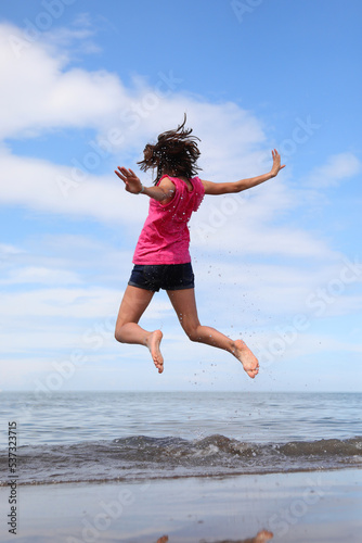 happy girl jumping and rejoicing for joy by the sea