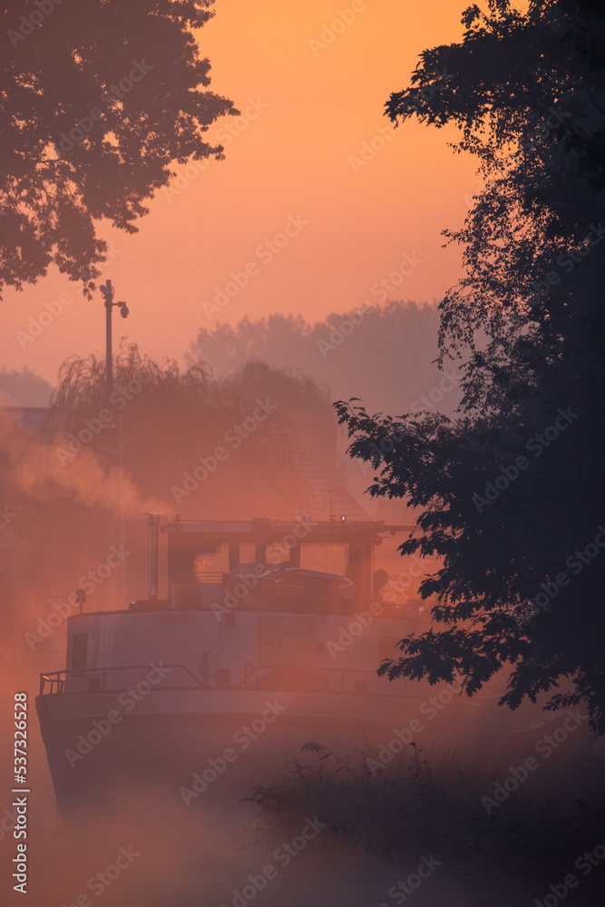 Silhouette of a cargo boat in the fiery red fog on a misty Morning on the River during sunrise. High quality photo Silhouette of a cargo boat in the fiery red fog on a misty Morning on the River during sunrise. High quality photo