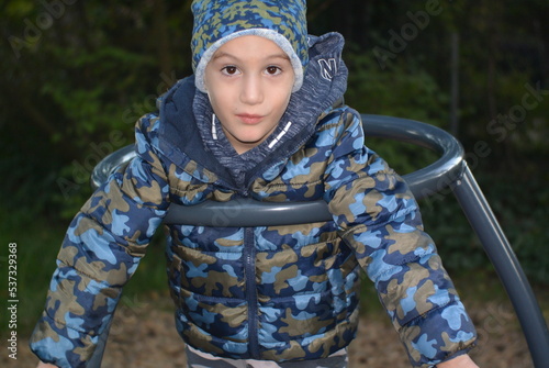 portrait of a child on a playground (merry go round) in a camouflage jacket 