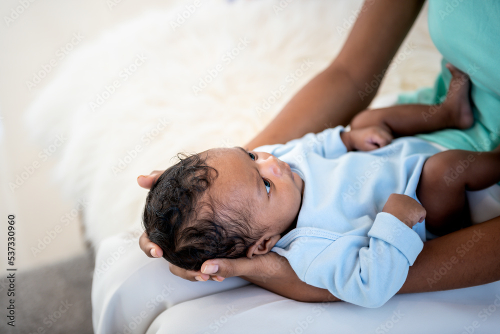half Nigeria half Thai, 1-month-old baby newborn son, looking at mother while his mother being held and sitting on a white bed, to relationship in family and infant newborn concept.