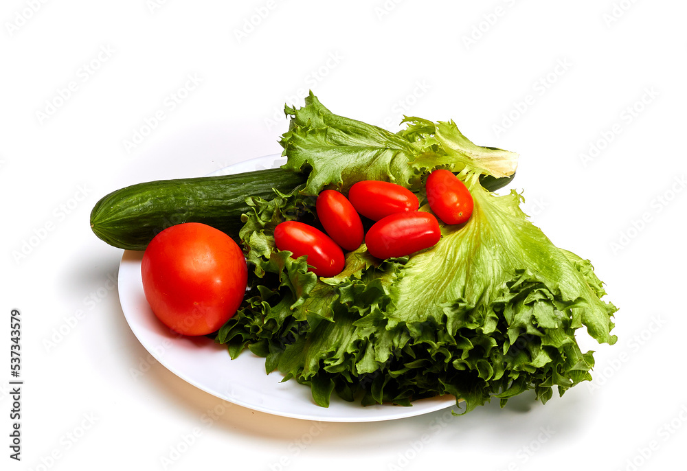 Fresh tomatoes, cucumber and lettuce on a white plate. Isolated. Fresh tomatoes, cucumber and lettuce on a white plate. Isolated.