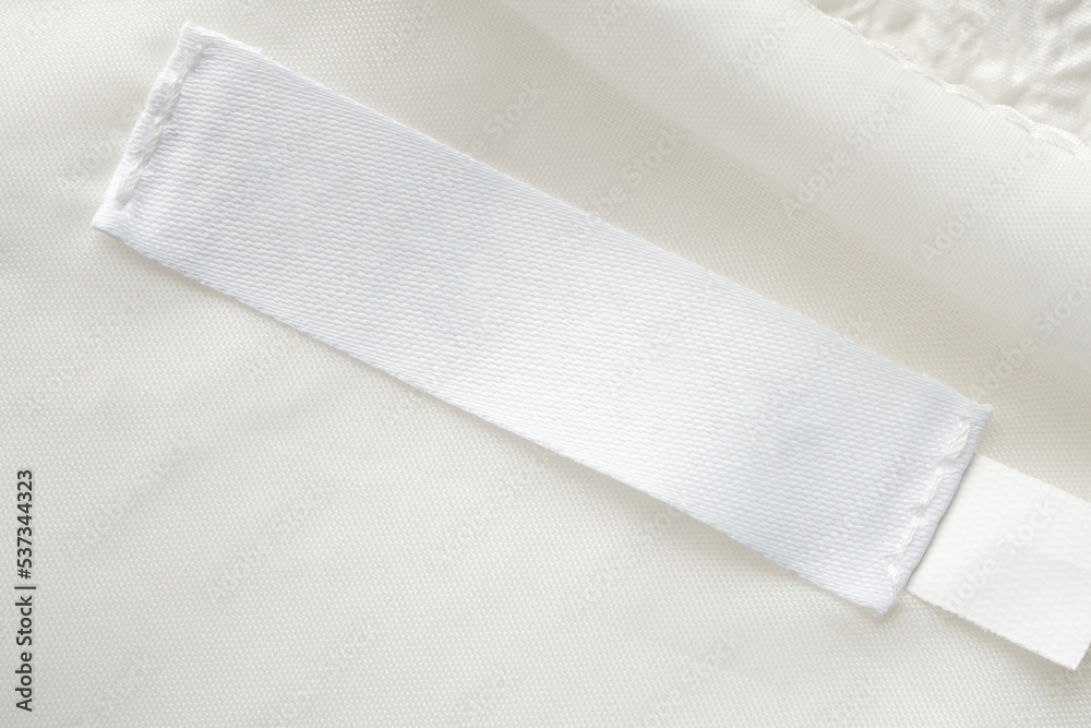 Blank white laundry care clothes label on fabric texture background Blank white laundry care clothes label on fabric texture background