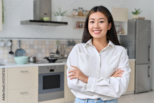Portrait of asian woman looking at camera over home kitchen interior