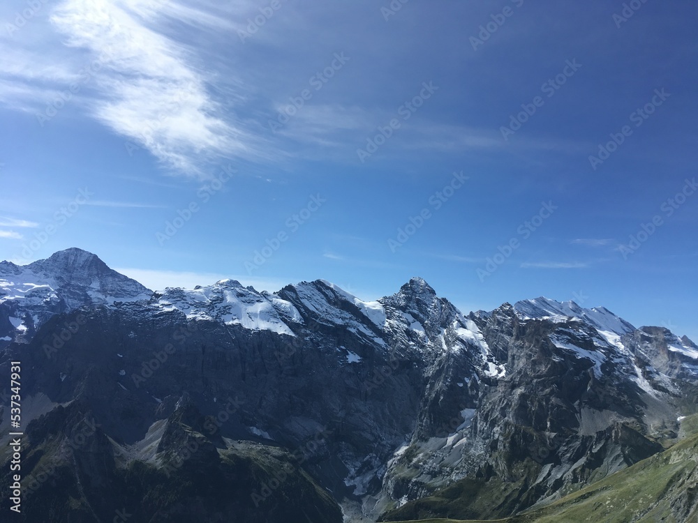 Obraz premium Huge mountains landscape view. Mountains in the summer sunny day in the Switzerland. Nature landscape with mountains, forest and green fields. Travel to Switzerland and mountain landscape. 