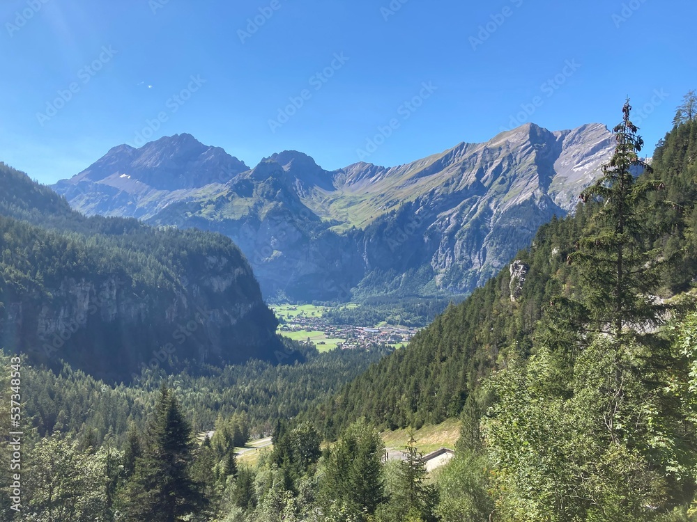 Mountains landscape on the summer day with blue sky. Switzerland mountain with rocks, trees and forest. Nature landscape view with mountains and lake. Lake in the mountains. 