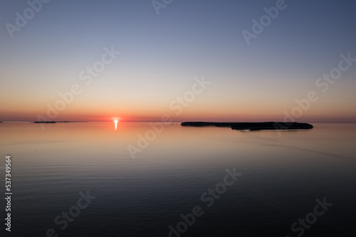Aerial drone view over the Baltic Sea with small island in distance. Magical sunset at beach.