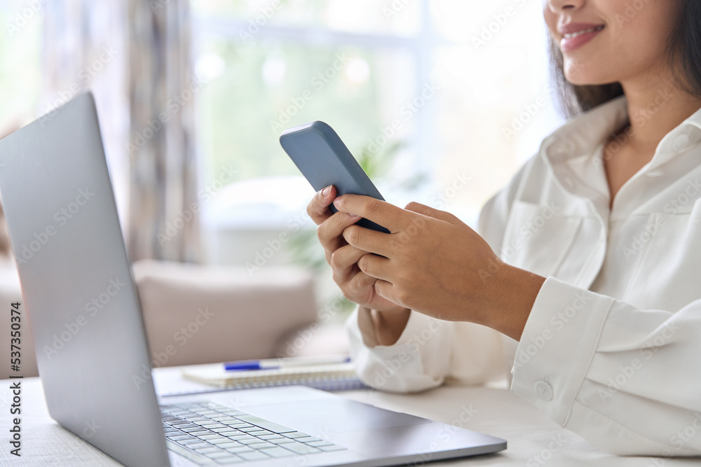 Closeup female hand with phone over desk with laptop computer Closeup female hand with phone over desk with laptop computer