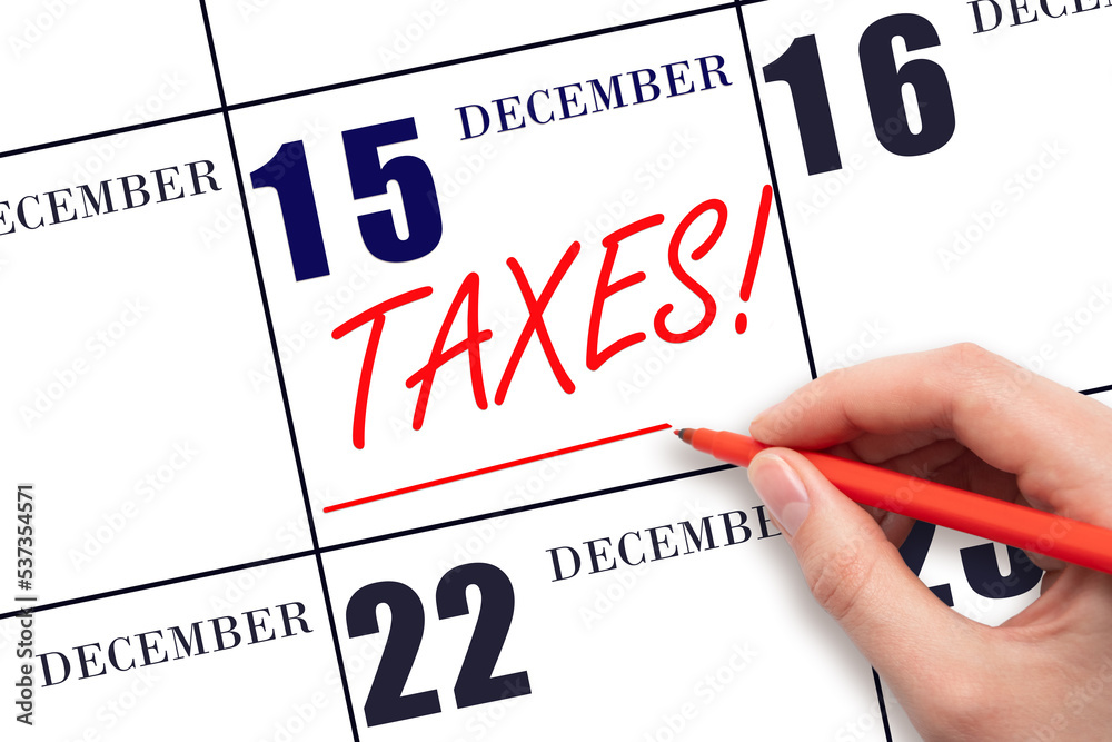 Hand drawing red line and writing the text Taxes on calendar date December 15. Remind date of tax payment Hand drawing red line and writing the text Taxes on calendar date December 15. Remind date of tax payment