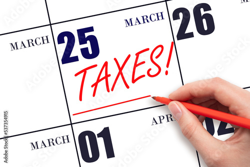 Hand drawing red line and writing the text Taxes on calendar date March 25. Remind date of tax payment