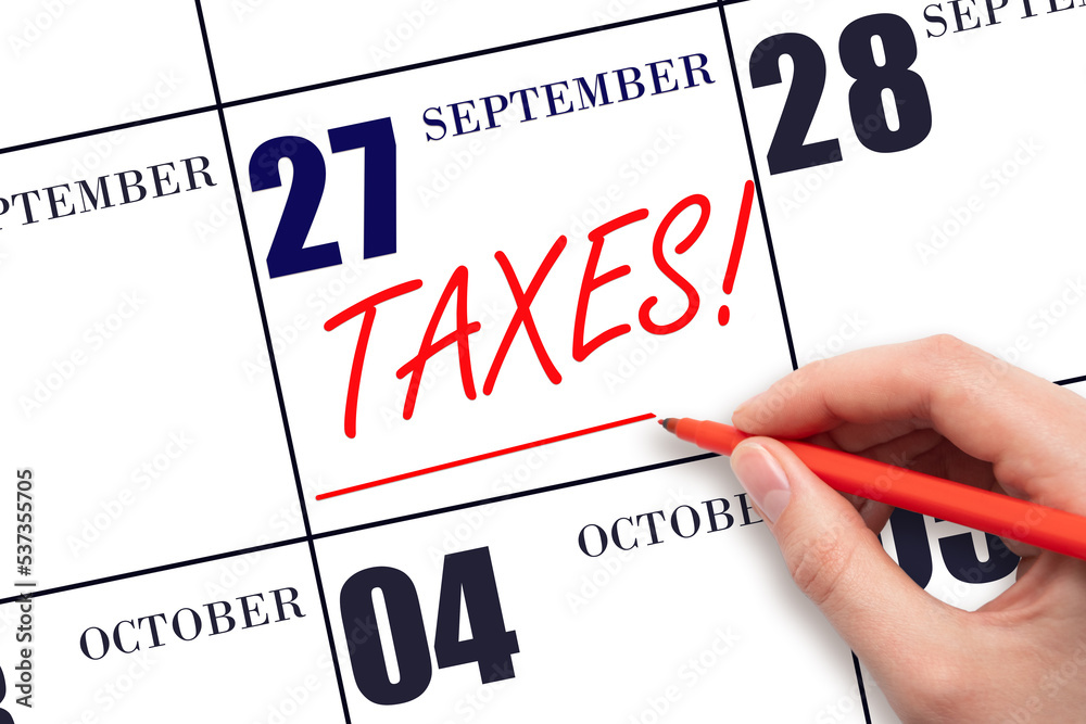 Hand drawing red line and writing the text Taxes on calendar date September 27. Remind date of tax payment Hand drawing red line and writing the text Taxes on calendar date September 27. Remind date of tax payment