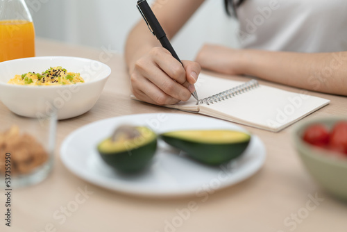 young female planning menu to eat ketogenic diet during weight loss program. photo