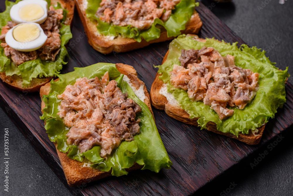 Delicious fresh sandwiches with toast, canned salmon, salad and quail eggs Delicious fresh sandwiches with toast, canned salmon, salad and quail eggs
