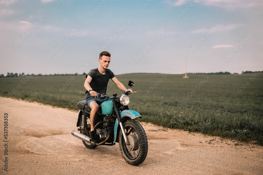 man on a classic retro motorcycle in the village, nostalgia for retro technology.