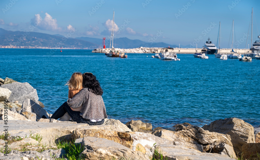 woman with little girl sitting by the sea