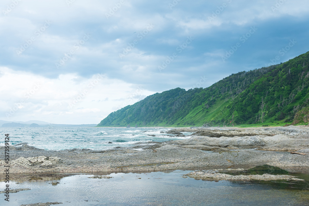coastal landscape, panorama with beautiful columnar basalt cliff on the wooded coast of Kunashir island coastal landscape, panorama with beautiful columnar basalt cliff on the wooded coast of Kunashir island