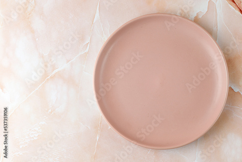 Empty pink blank plate on beige pink marble background. Minimalist mock up for product presentation.