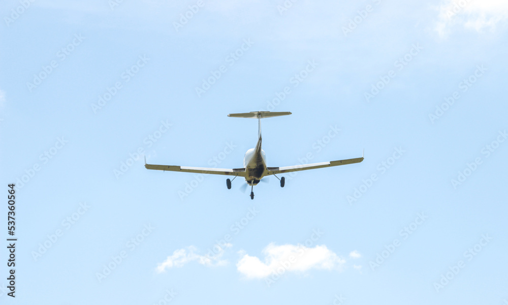 A single-engine plane is flying in the sky among the clouds. A light-engine plane in the blue sky flies through the clouds. A single-engine plane is flying in the sky among the clouds. A light-engine plane in the blue sky flies through the clouds.