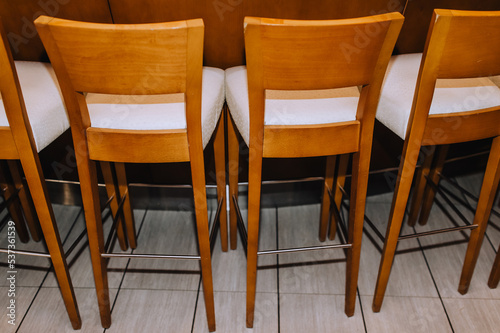 Wooden brown vintage chairs stand in a row indoors.