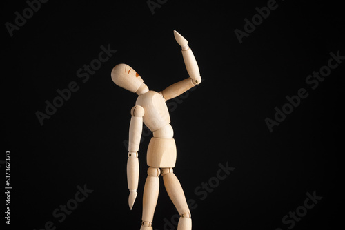 wooden figure in a pose, bored, grief, broken. Black background