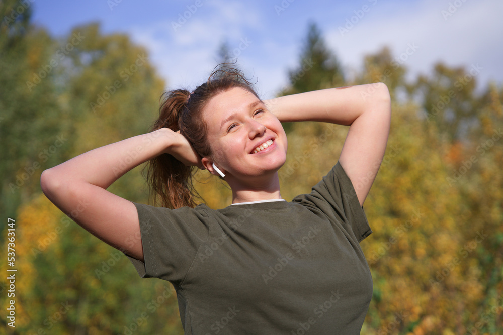 portrait of beautiful happy girl, young positive woman standing in golden autumn forest or park, listening to music in wireless earphones smiling on natural background, breathing deep deeply fresh air portrait of beautiful happy girl, young positive woman standing in golden autumn forest or park, listening to music in wireless earphones smiling on natural background, breathing deep deeply fresh air