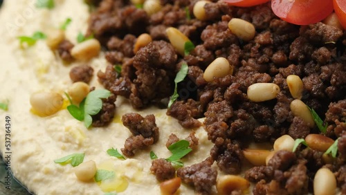 Hummus with spiced ground beef, olive oil, tomatoes and toasted pine nuts. Rotating video