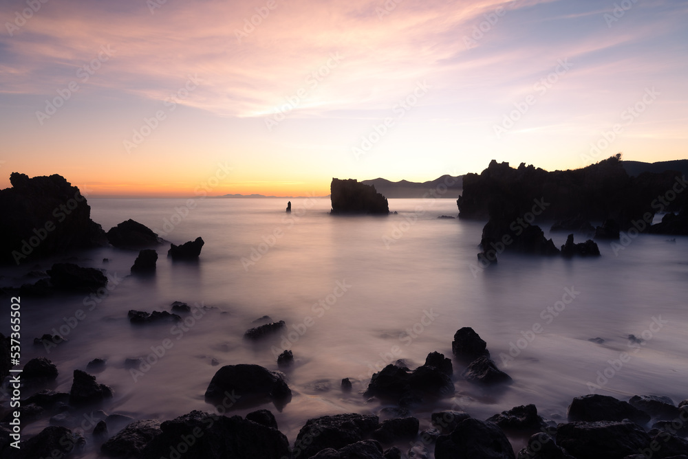 Beautiful long exposure scenic view of the rocky coastline in the Cantabrian sea at dawn, Noja, Cantabria, Spain