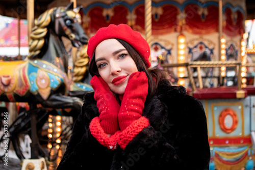 beautiful girl in a red beret and mittens in winter on New Year's street.