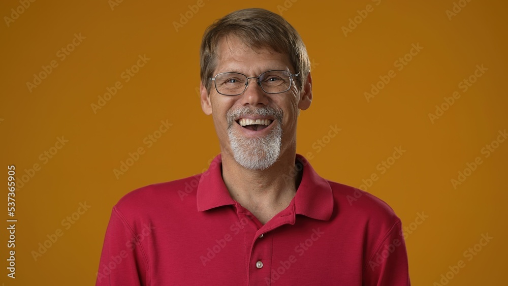 Portrait face of happy smiling mature man expressing joy and laughing with an open mouth. Mature male reacting to funny joke isolated on yellow background. Portrait face of happy smiling mature man expressing joy and laughing with an open mouth. Mature male reacting to funny joke isolated on yellow background.