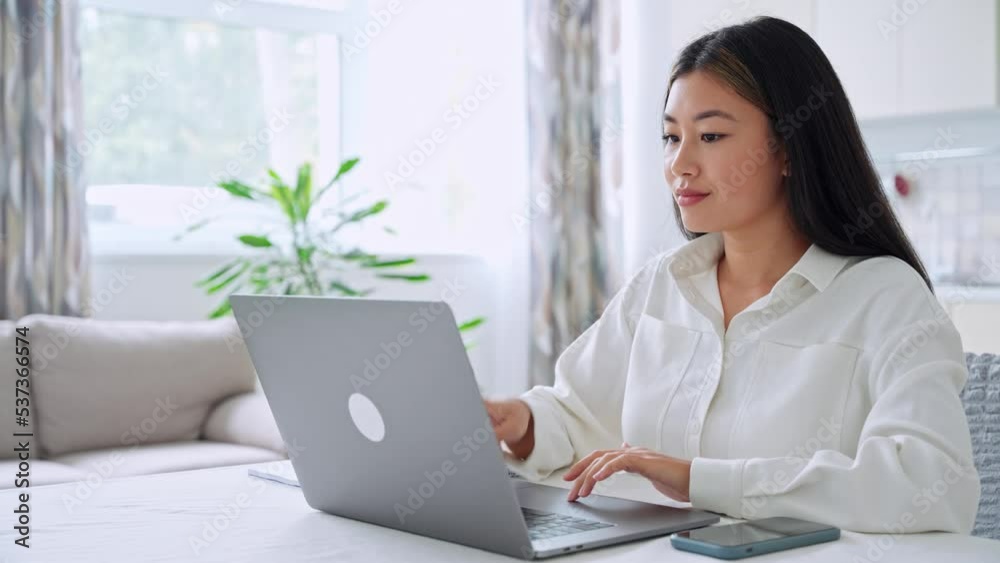 Young smiling asian student freelancer woman using laptop for remote work Young smiling asian student freelancer woman using laptop for remote work