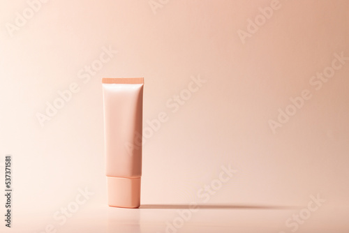 Fotografie Cosmetic cream or mask in a white tube with hard shadows from the leaves on a white background
