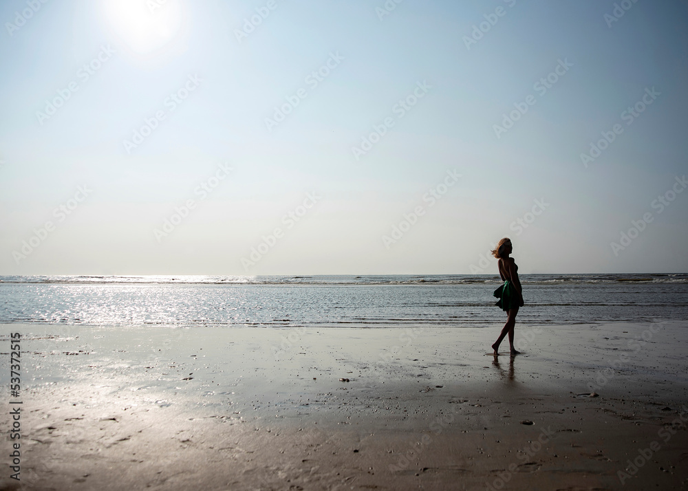 Mädchen im Kleid steht am Strand