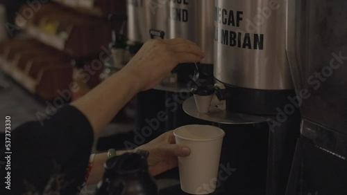 This video shows an anonymous hand pouring decaf coffee in a to go cup at a cafe.