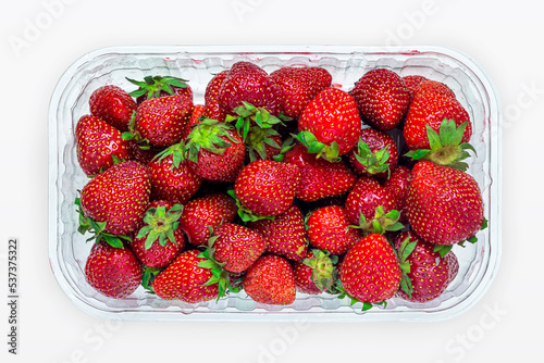 Top view of a package with ripe bright red strawberries on a white background