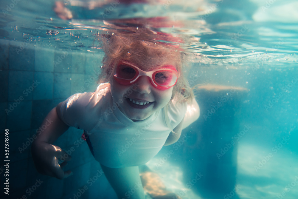 Naklejka premium Happy child toddler fun swimming underwater in swimming pool
