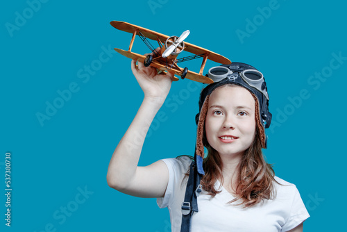 Girl with a toy plane. A symbol of travel and development - a teenager dreams of flying. Young girl-pilot against the blue sky